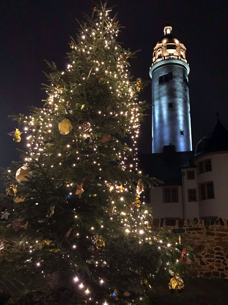 Der Höchster Geschichtsverein wünscht frohe Weihnachten und gibt einen Jahresrückblick auf 2019. Zu sehen ist der festlich geschmückte Weihnachtsbaum auf dem Höchster Schlossplatz, im Hintergrund der beleuchtete Schlossturm in der Höchster Altstadt.