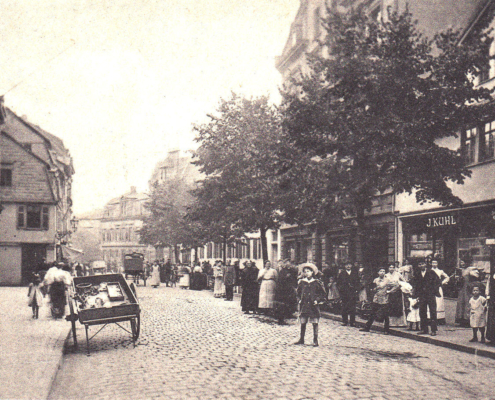 Zu sehen ist der alte Höchster Marktplatz zwischen 1900 und 1914 mit Marktständen vor dem Antoniterkloster in der ehemaligen Hauptstrasse, der heutigen Bolongarostraße in Frankfurt-Höchst. Historische Postkarte. Exemplar im Archiv des Vereins für Geschichte und Altertumskunde e.V. Frankfurt-Höchst.